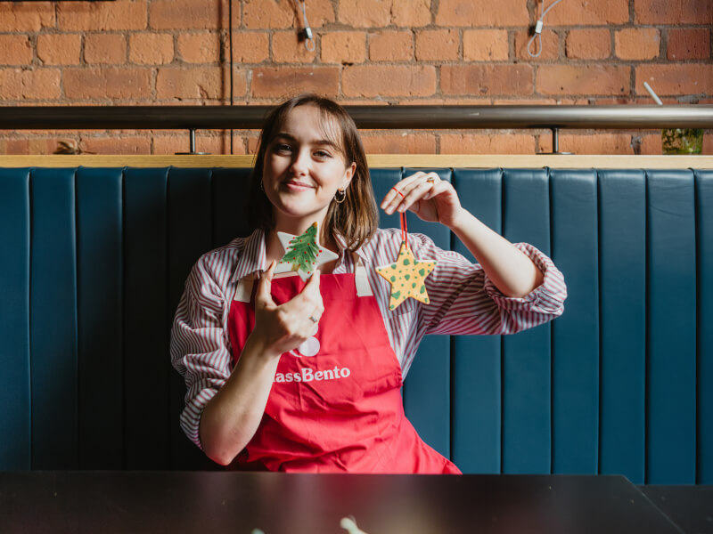 Woman holding up finished ceramic Christmas ornaments